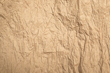 Wrinkled beige kraft paper background in sunlights