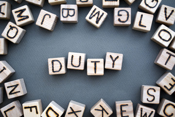 the word duty wooden cubes with burnt letters, duties of people, gray background top view, scattered cubes around random letters