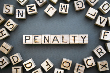 the word penalty wooden cubes with burnt letters, penalty for tax evasion, gray background top view, scattered cubes around random letters