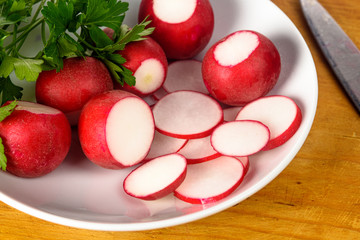 Radish and parsley on a white plate. The plate and the knife on the Board