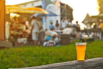 Naklejka premium Beer in a plastic glass close-up. Alcoholic beverage at the festival. Bakal on a wooden board against the background of the scene.