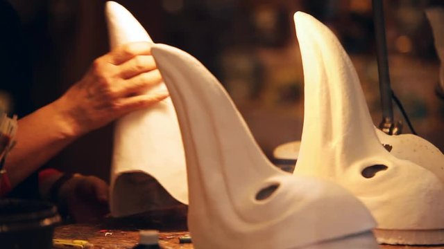 Venetian artist works on a traditional beaked carnival masks painting them