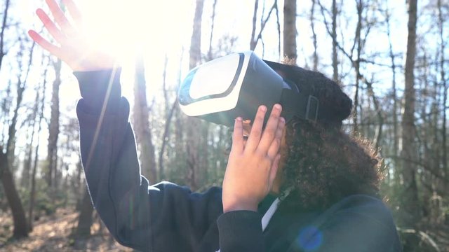 4K video clip of beautiful mixed race African American girl teenager female young woman using virtual reality VR headset in a forest woodland environment