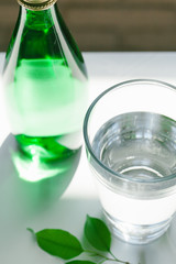 Glass of water with a bottle on table