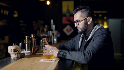 Man using smartphone near glass of drink on bar counter