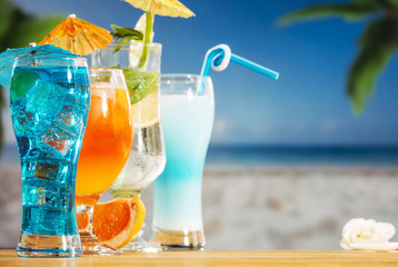 Blue orange drinks with sliced lime mint ice cubes in bright umbrella decorated glasses