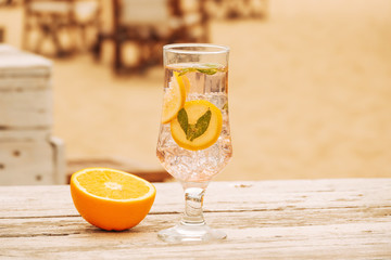 Glass of chilling mint drink and sliced orang on wooden surface