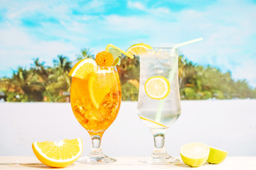 Glasses of juicy orange lemon drinks with straw and sliced citruses