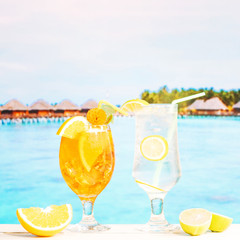 Glasses of juicy lemon orange drinks with straw and sliced citruses