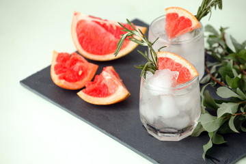 Glass of refreshing grapefruit drink with rosemary on table, summer resort menu, bar cart concept, copy space