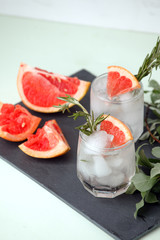 Glass of refreshing grapefruit drink with rosemary on table, summer resort menu, bar cart concept, copy space