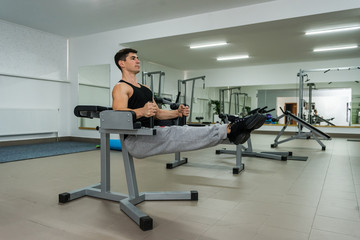 Young and sportive man making stretching exercises in gym