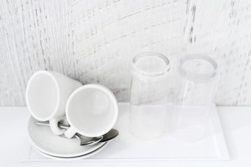 Coffee and tea making set of white cups, saucers, tea spoons and glasses on white porcelain tray. Hotel accomodation. Copy space.