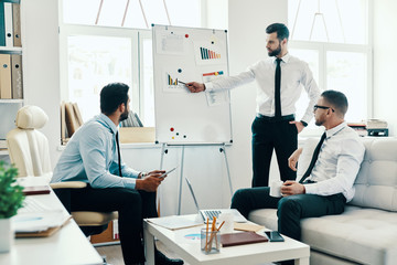 Developing new strategy. Young modern man in formalwear conducting a business presentation using flipchart while working in the office