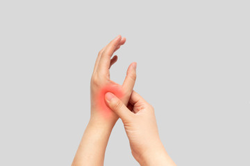 Young female suffering from pain in hands and massaging her painful hands isolated gray background....