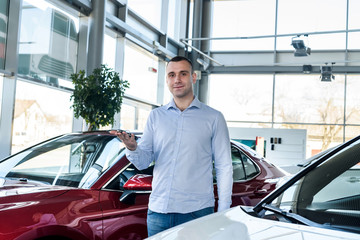 Man in showroom holding keys from new car