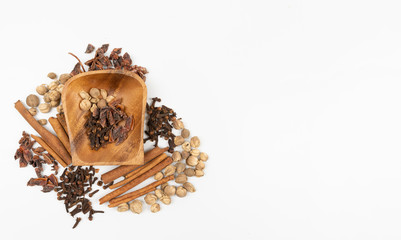 top view isolated dried spices such as cardamom clove cinnamon and nutmeg placed around wooden bowl with put some sweet basil, alternative drugs or nature medicine concept,