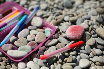 Close up of hand-painted colorful stones on a pebble beach on a summer morning. Kids activities. 