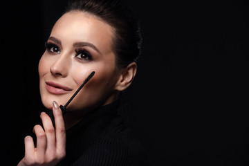 Beauty Cosmetics.Woman applying black mascara on eyelashes with makeup brush. photos of appealing...