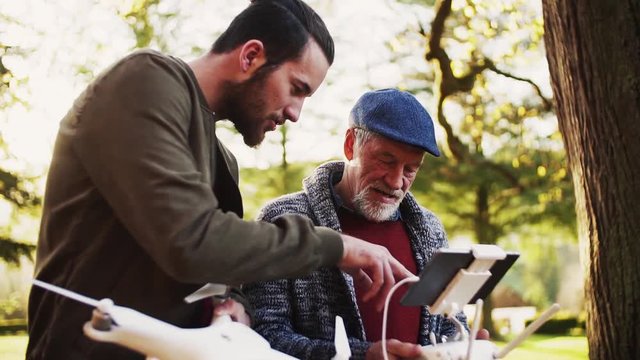 Senior father and his son with drone in nature, talking. Slow motion.