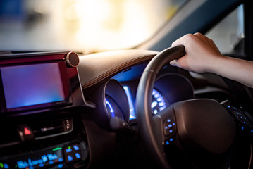 Male driver hand holding on steering wheel using digital dashboard monitor for GPS navigation on...