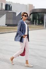 Beautiful emancipated business woman walking on City street. Determination fashionable woman wears...