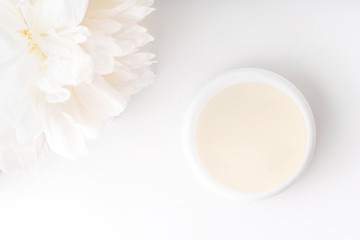White peony and mockup face and body cream on white background. Cosmetics concept. Flat lay.