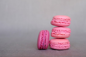 Stack of delicious french pink strawberry and blackberry flavour macarons on grey background
