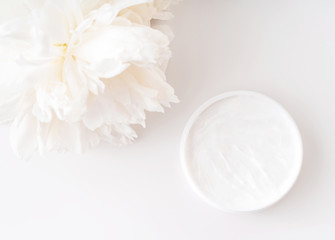 White peony and mockup face and body cream on white background. Cosmetics concept. Flat lay.