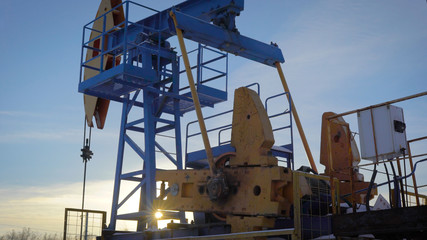 Fototapeta na wymiar pumpjack on an oil well in winter forest in daytime, extraction of petroleum in northern countries