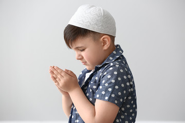 Little Muslim boy praying against light background