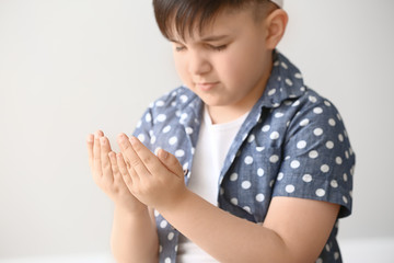 Little Muslim boy praying against light background