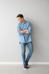 Fototapeta premium Fashionable young man near light wall