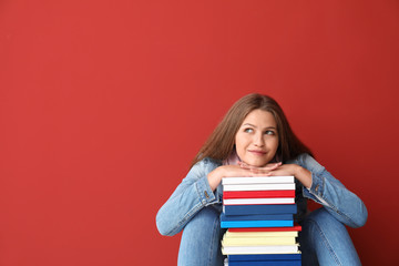 Beautiful young woman with books on color background