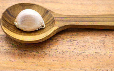 Garlic cloves in a spoon on a wooden background