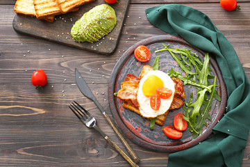 Plate with tasty grilled bread, fried egg and bacon on wooden table