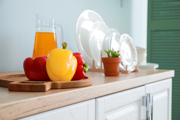 Fresh pepper, juice and dishware on table in kitchen