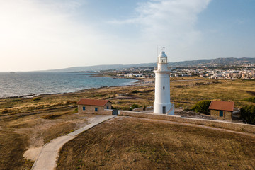 Fototapeta na wymiar Aerial view on the deserted coast and a white lighthouse at the sunset, Paphos Cyprus