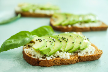 Tasty sandwiches with avocado on light color background, closeup