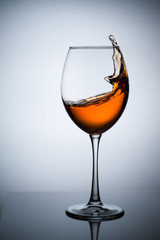 Amber wine. A splash of wine in a glass. Liquid in a glass. Traditional wine according to the ancient Georgian technology. Concept with a glass of wine. Copy space. Close up and vertical orientation.