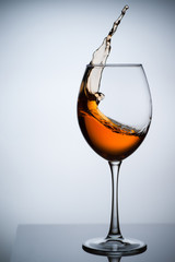 Amber wine. A splash of wine in a glass. Liquid in a glass. Traditional wine according to the ancient Georgian technology. Concept with a glass of wine. Copy space. Close up and vertical orientation.