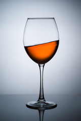 Amber wine. A splash of wine in a glass. Liquid in a glass. Traditional wine according to the ancient Georgian technology. Concept with a glass of wine. Copy space. Close up and vertical orientation.