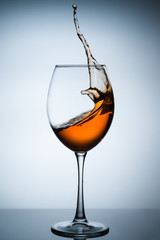 Amber wine. A splash of wine in a glass. Liquid in a glass. Traditional wine according to the ancient Georgian technology. Concept with a glass of wine. Copy space. Close up and vertical orientation.
