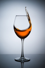 Amber wine. A splash of wine in a glass. Liquid in a glass. Traditional wine according to the ancient Georgian technology. Concept with a glass of wine. Copy space. Close up and vertical orientation.