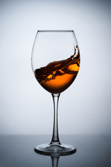 Amber wine. A splash of wine in a glass. Liquid in a glass. Traditional wine according to the ancient Georgian technology. Concept with a glass of wine. Copy space. Close up and vertical orientation.