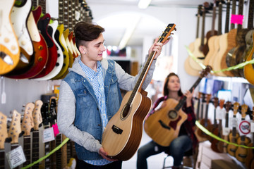 Teenagers examining guitars in shop