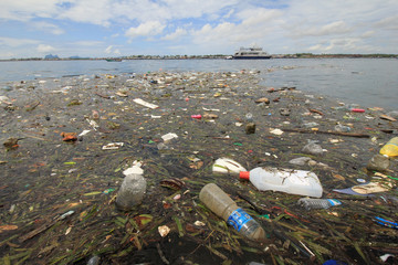 Plastic and styrofoam bottles, bags and food containers dumped in river and flow into sea