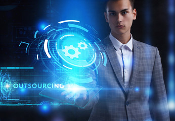 The concept of business, technology, the Internet and the network. A young entrepreneur working on a virtual screen of the future and sees the inscription: Outsourcing