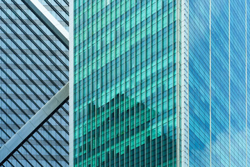 Closeup view of generic modern office skyscrapers ,high rise buildings with abstract geometry glass facades on a bright sunny day . Concepts of finances and economics background.