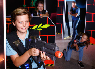 Excited boy aiming laser gun at other players during laser tag g